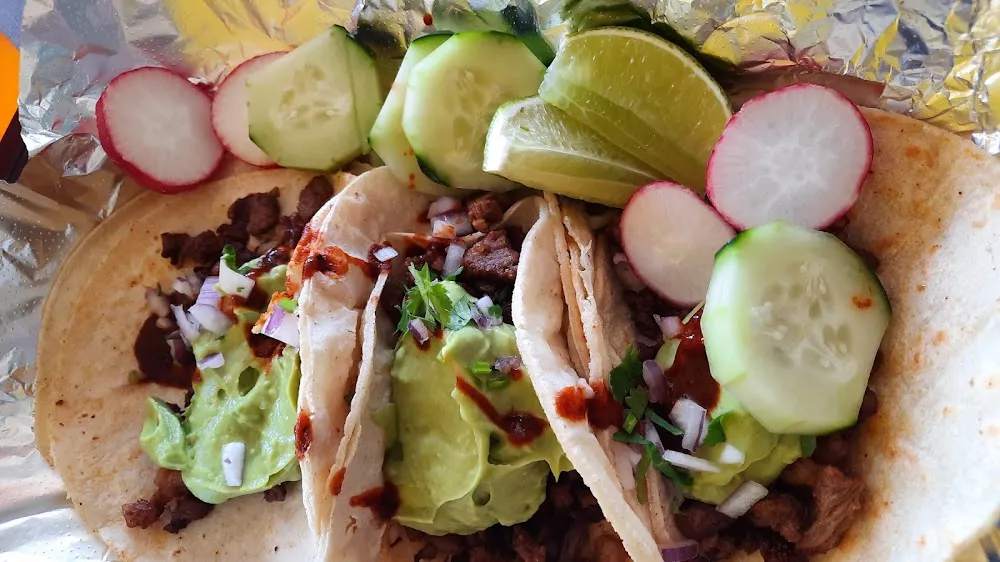 Asada Tacos with Guacamole Salsa Radishes Cucumbers Red Sauce and Lemon